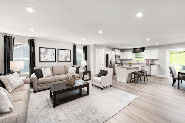 living room with light wood-style floors, recessed lighting, and baseboards