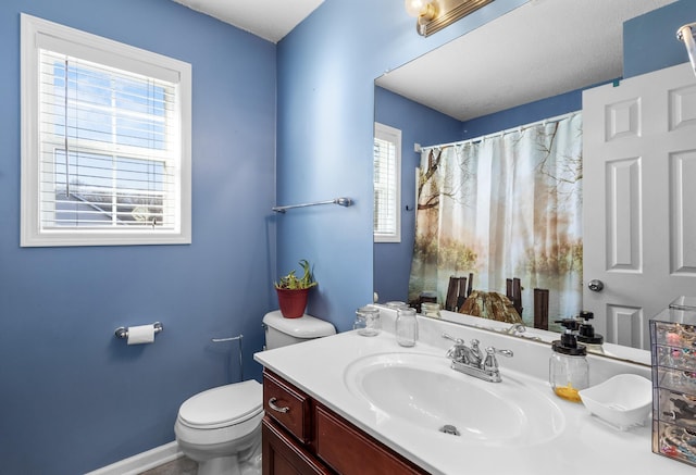 bathroom with a shower with shower curtain, vanity, toilet, and baseboards