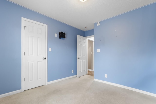 unfurnished bedroom featuring carpet floors, a textured ceiling, and baseboards