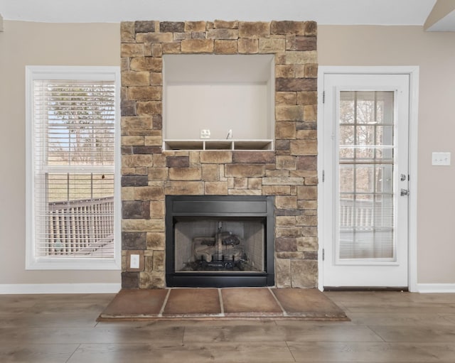 room details featuring a fireplace, baseboards, and wood finished floors