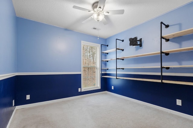 empty room featuring carpet floors, visible vents, a ceiling fan, and a textured ceiling