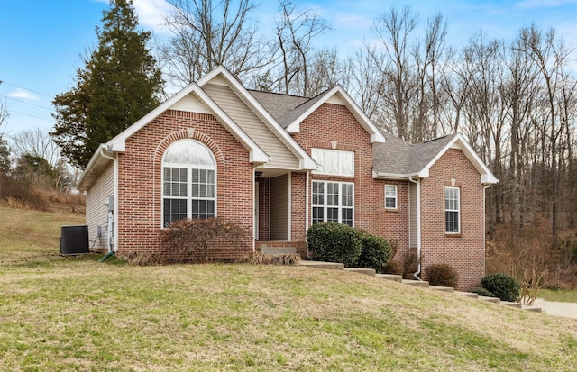 view of front of property with central AC unit, brick siding, roof with shingles, and a front yard