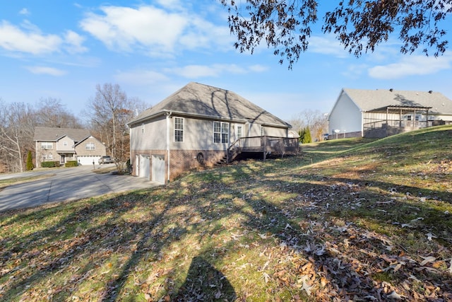 view of property exterior featuring an attached garage, a deck, concrete driveway, and brick siding