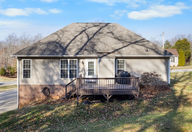 rear view of house featuring a shingled roof, brick siding, and a wooden deck