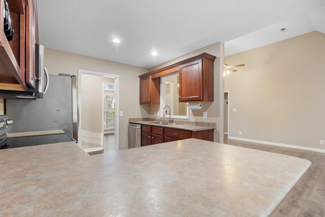 kitchen with a sink, a ceiling fan, light countertops, appliances with stainless steel finishes, and light wood-type flooring