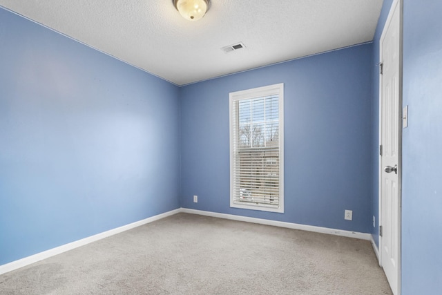 empty room with carpet, visible vents, baseboards, and a textured ceiling