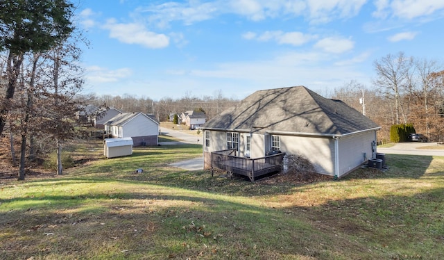 view of side of property featuring central AC unit, a lawn, a shingled roof, and a wooden deck