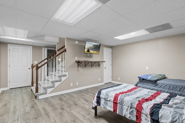 bedroom with a paneled ceiling, baseboards, and wood finished floors