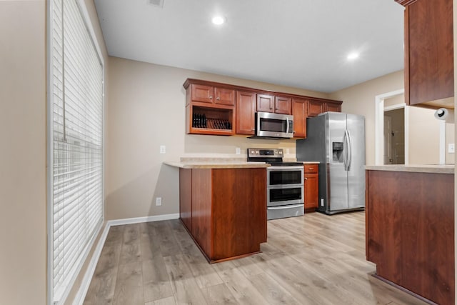 kitchen featuring a peninsula, light wood-style flooring, appliances with stainless steel finishes, and light countertops