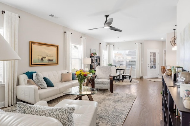 living room with ceiling fan, wood finished floors, visible vents, and baseboards