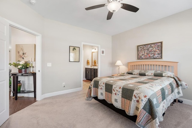 bedroom with a ceiling fan, light colored carpet, baseboards, and ensuite bathroom