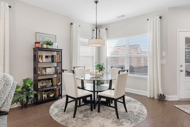 dining room with dark wood-style flooring, visible vents, and baseboards