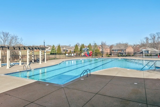 community pool featuring a patio, playground community, fence, a pergola, and a residential view