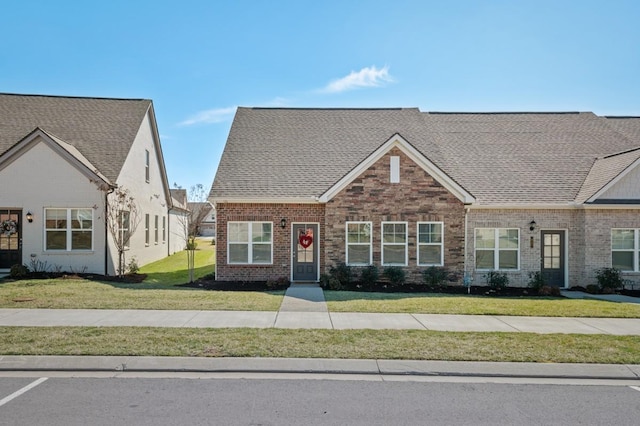 craftsman house with brick siding, a front lawn, and roof with shingles