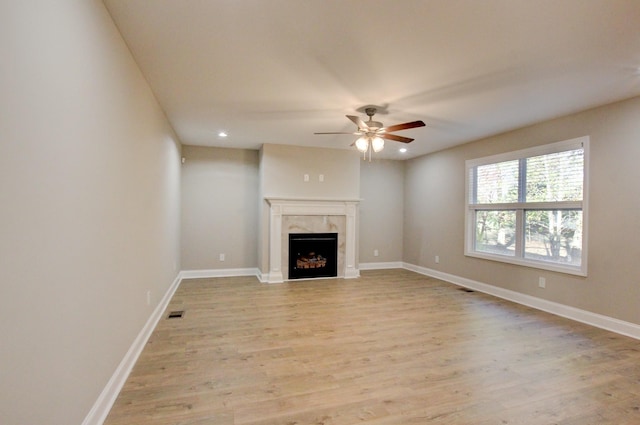 unfurnished living room featuring a premium fireplace, light wood-type flooring, and baseboards