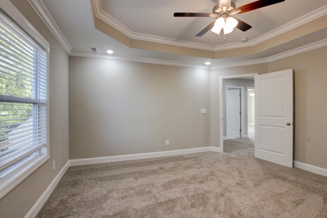 empty room featuring carpet floors, a tray ceiling, crown molding, and baseboards