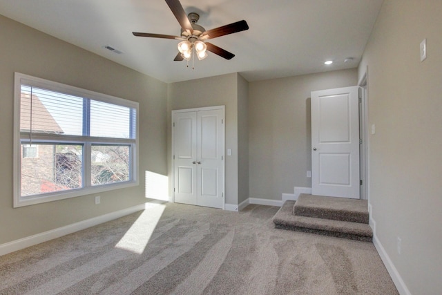 unfurnished bedroom with a closet, visible vents, carpet flooring, ceiling fan, and baseboards