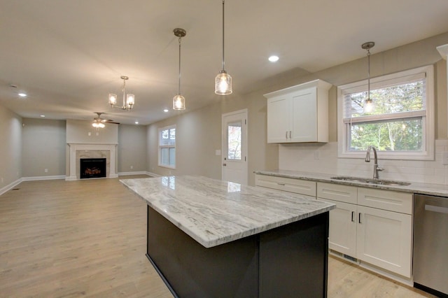 kitchen featuring decorative backsplash, dishwasher, a premium fireplace, a kitchen island, and a sink