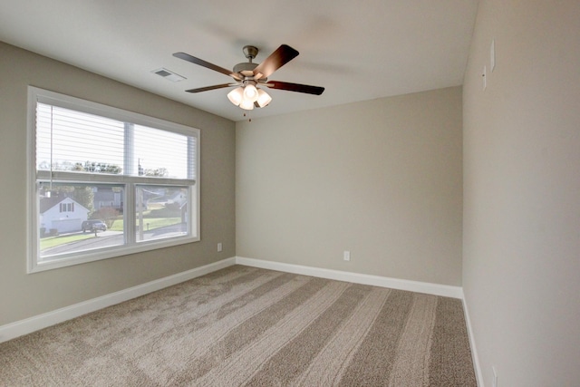 carpeted spare room with visible vents, ceiling fan, and baseboards