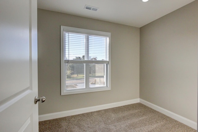 carpeted spare room with visible vents and baseboards