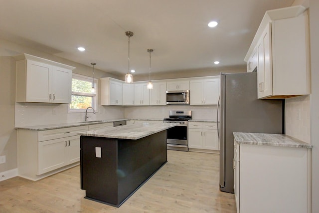 kitchen with tasteful backsplash, light wood-style flooring, appliances with stainless steel finishes, white cabinets, and a sink