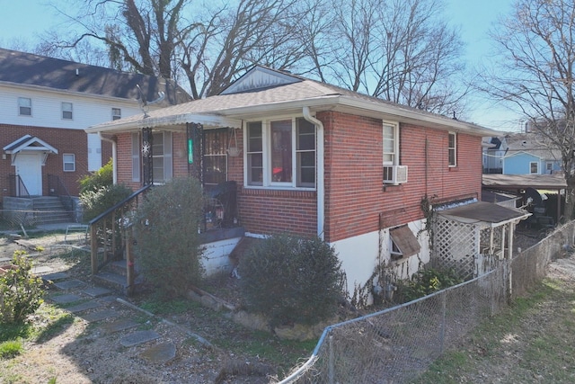 view of property exterior with roof with shingles, fence, cooling unit, and brick siding