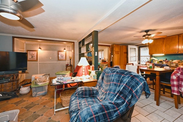 living area featuring ceiling fan and a textured ceiling