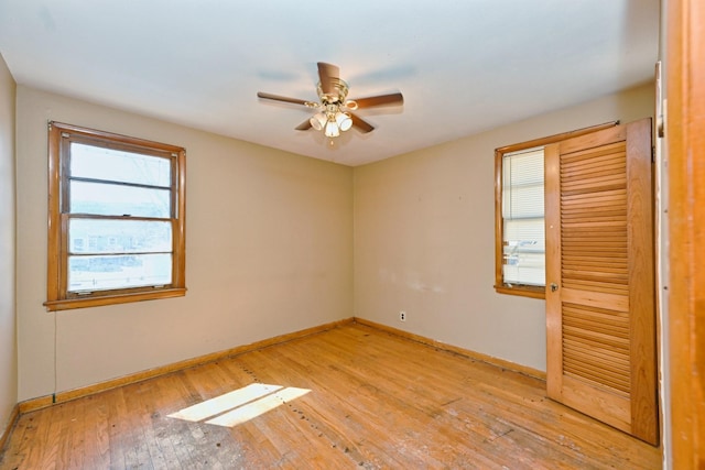 unfurnished room with ceiling fan, light wood finished floors, and baseboards