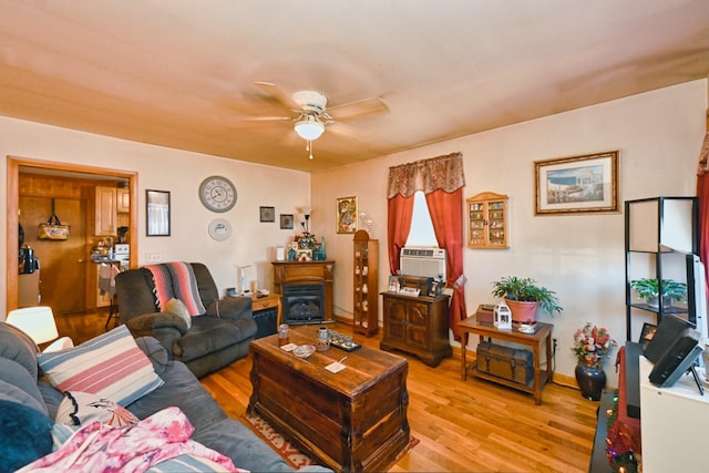 living area featuring light wood-type flooring, a fireplace, cooling unit, and a ceiling fan