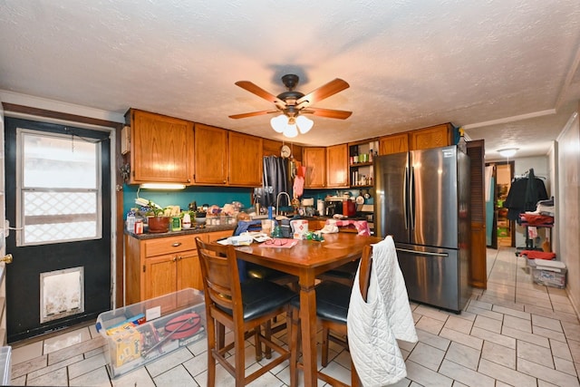 kitchen with brown cabinetry, dark countertops, freestanding refrigerator, a textured ceiling, and open shelves