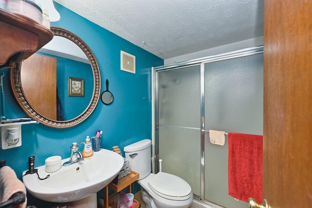 full bath featuring a textured ceiling, a stall shower, a sink, and visible vents