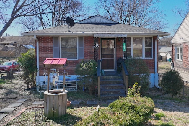 bungalow featuring brick siding and a shingled roof