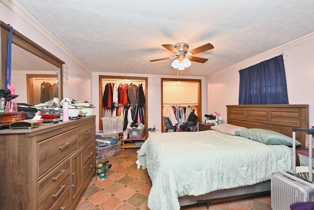 bedroom featuring crown molding, a textured ceiling, ceiling fan, and two closets