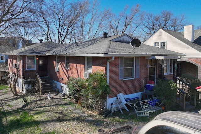 view of front of house with entry steps, brick siding, roof with shingles, and cooling unit