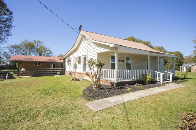 view of front of property with covered porch, metal roof, and a front lawn