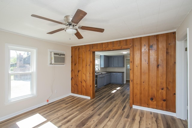 interior space with dark wood-style floors, a wall mounted AC, ornamental molding, a sink, and baseboards