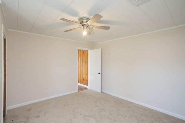 carpeted empty room featuring ornamental molding, baseboards, and a ceiling fan