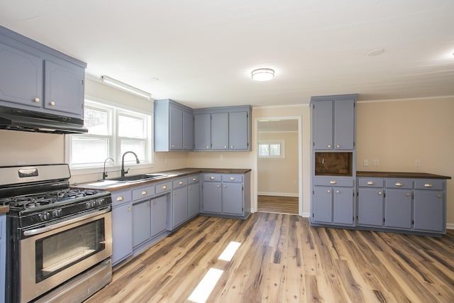 kitchen with gray cabinetry, stainless steel gas stove, a sink, plenty of natural light, and under cabinet range hood