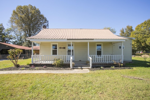 view of front of property featuring a porch, a front yard, and metal roof