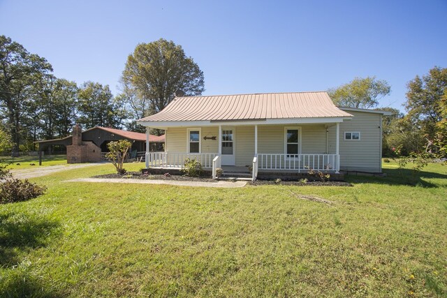 view of front of property with a front yard, covered porch, and metal roof