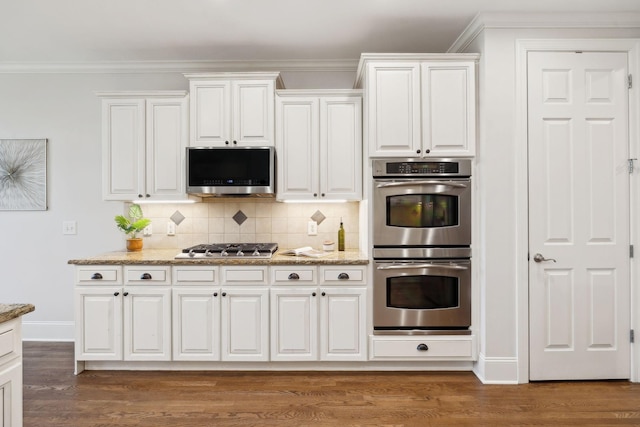 kitchen with ornamental molding, appliances with stainless steel finishes, white cabinets, and tasteful backsplash