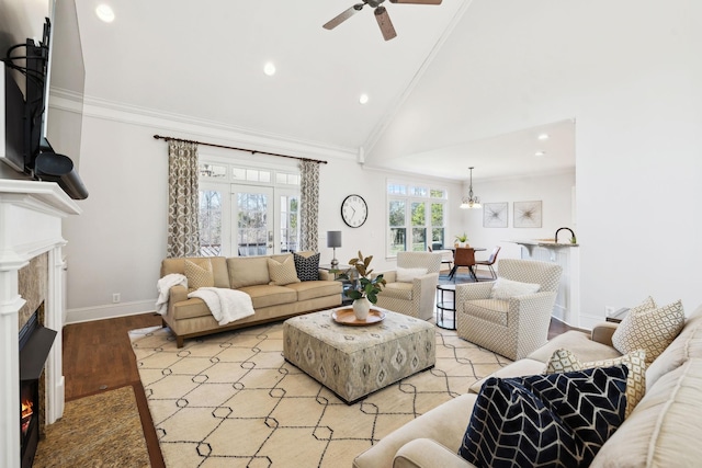 living room featuring a warm lit fireplace, recessed lighting, baseboards, light wood-type flooring, and crown molding