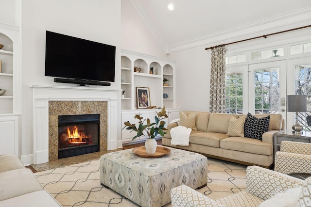 living room with high vaulted ceiling, ornamental molding, built in features, and a high end fireplace