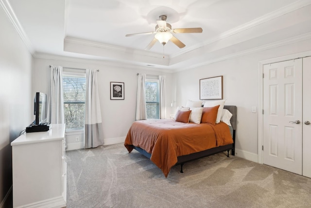 bedroom with multiple windows, a raised ceiling, and light colored carpet