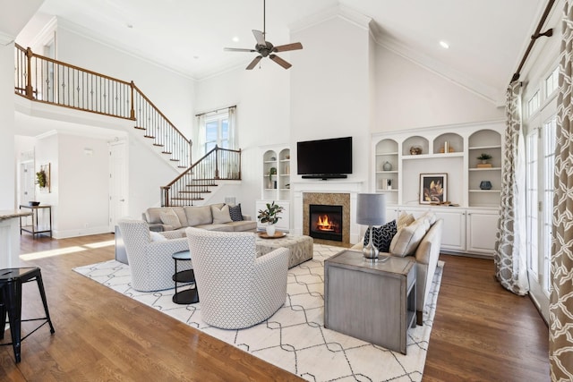 living area featuring high vaulted ceiling, a fireplace, crown molding, and light wood-style flooring