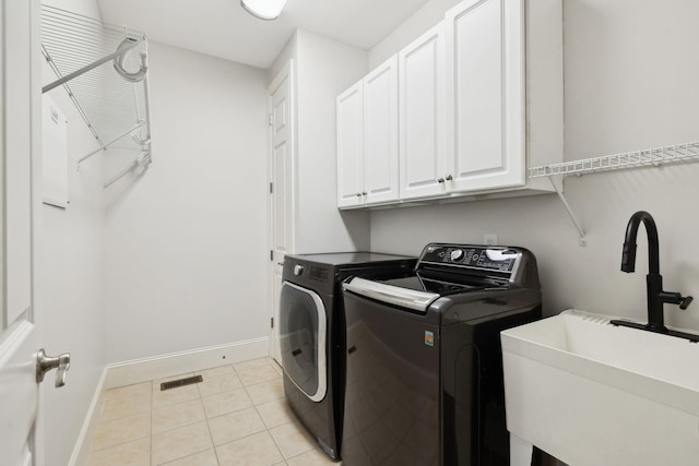 laundry area with washer and clothes dryer, light tile patterned floors, cabinet space, a sink, and baseboards