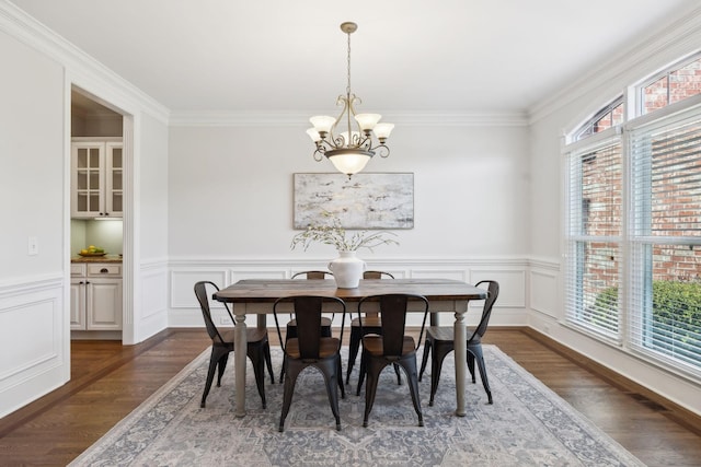 dining area featuring dark wood-style floors, ornamental molding, a wealth of natural light, and a notable chandelier