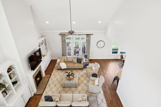 living area with ceiling fan, baseboards, wood finished floors, and ornamental molding