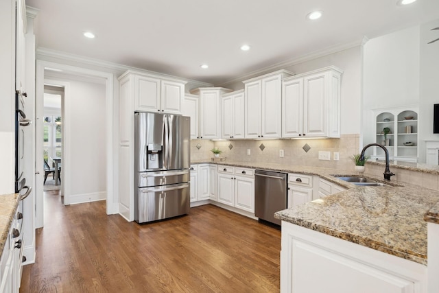 kitchen with appliances with stainless steel finishes, wood finished floors, a sink, and ornamental molding