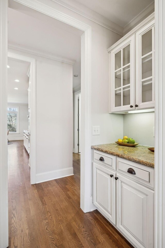 bar with ornamental molding, dark wood-style flooring, and baseboards